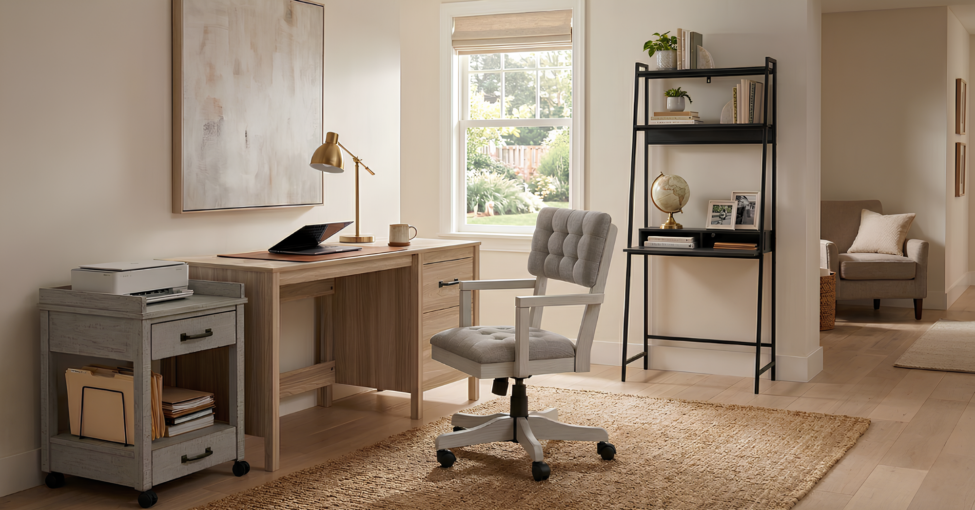 Light wood desk, grey tufted rolling office chair, and a black leaning shelf in a sunlit room, showcasing our modern home office furniture in Surrey.